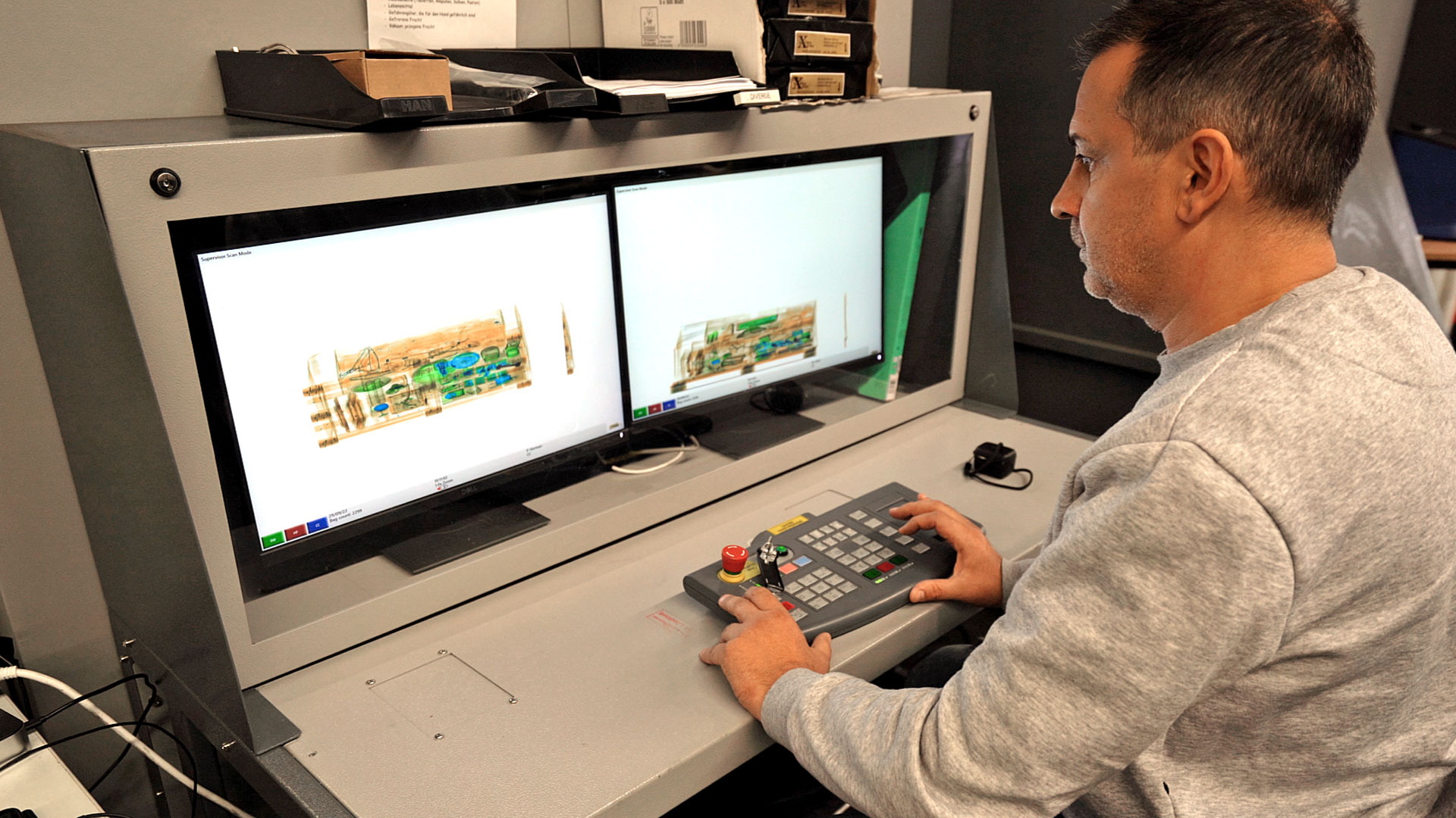 Luftsicherheitskontrollkraft sitzt am Monitor des Frachtröntgengeräts